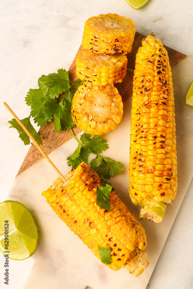 Board with tasty grilled corn cobs and parsley on white background