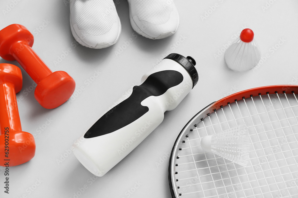 Set of sports equipment, shoes and bottle of water on light background