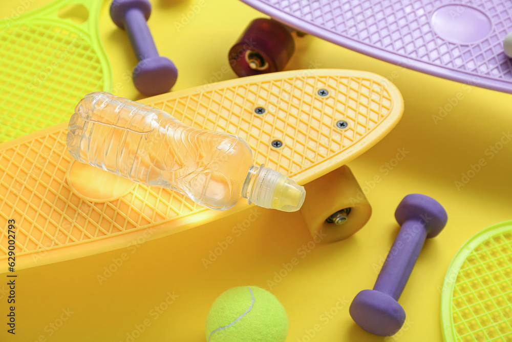 Composition with different sports equipment and bottle of water on yellow background, closeup