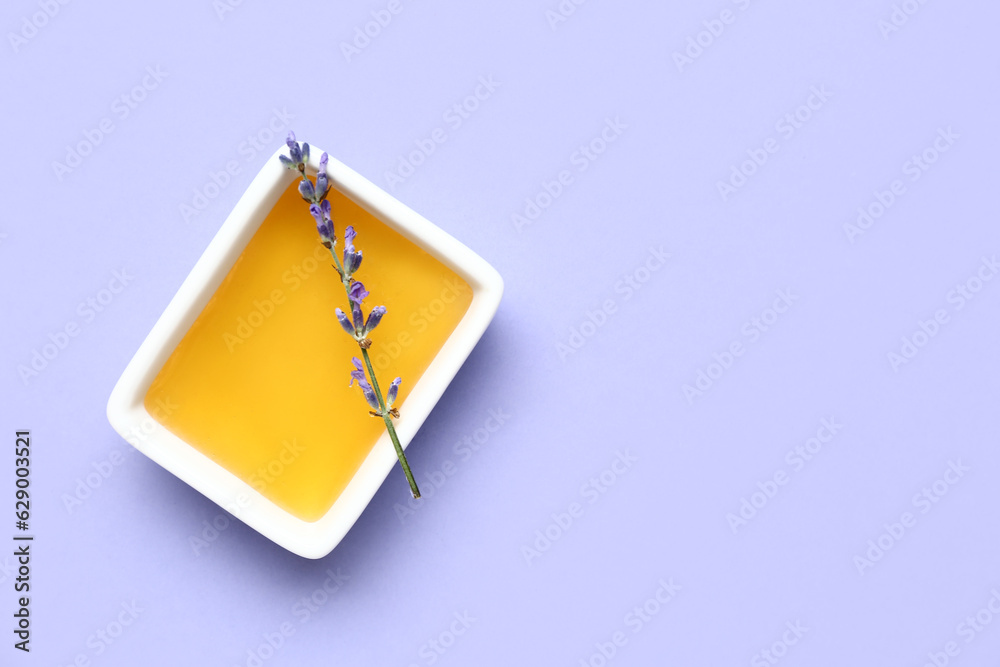 Bowl of sweet lavender honey on blue background