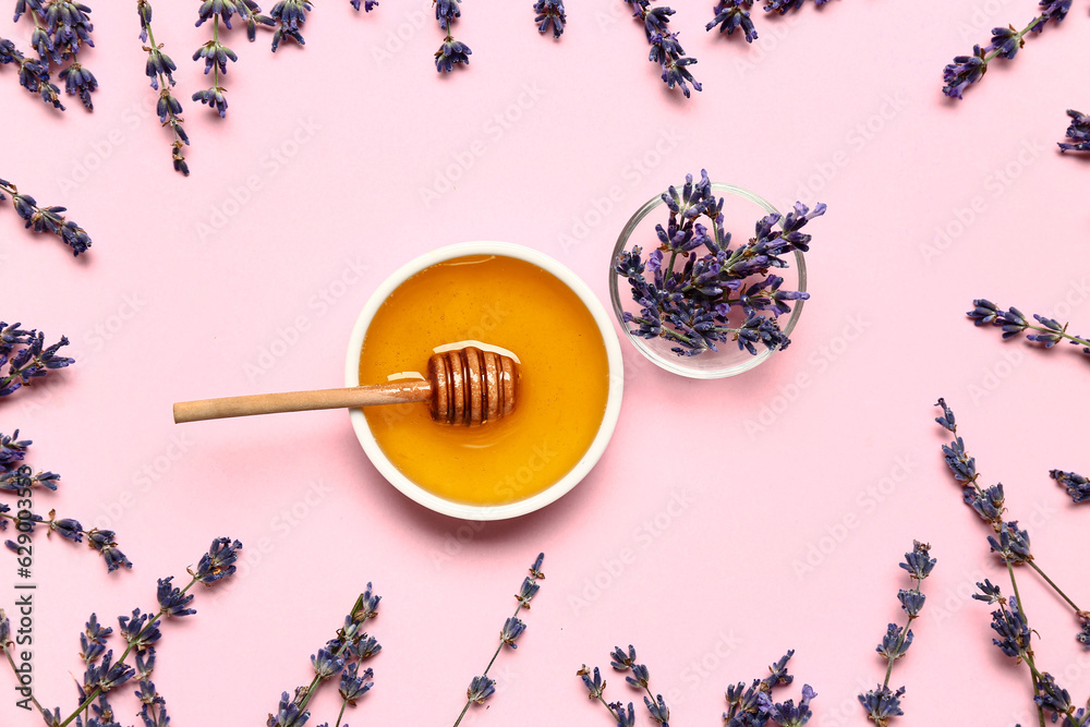 Bowl of sweet lavender honey, dipper and flowers on pink background