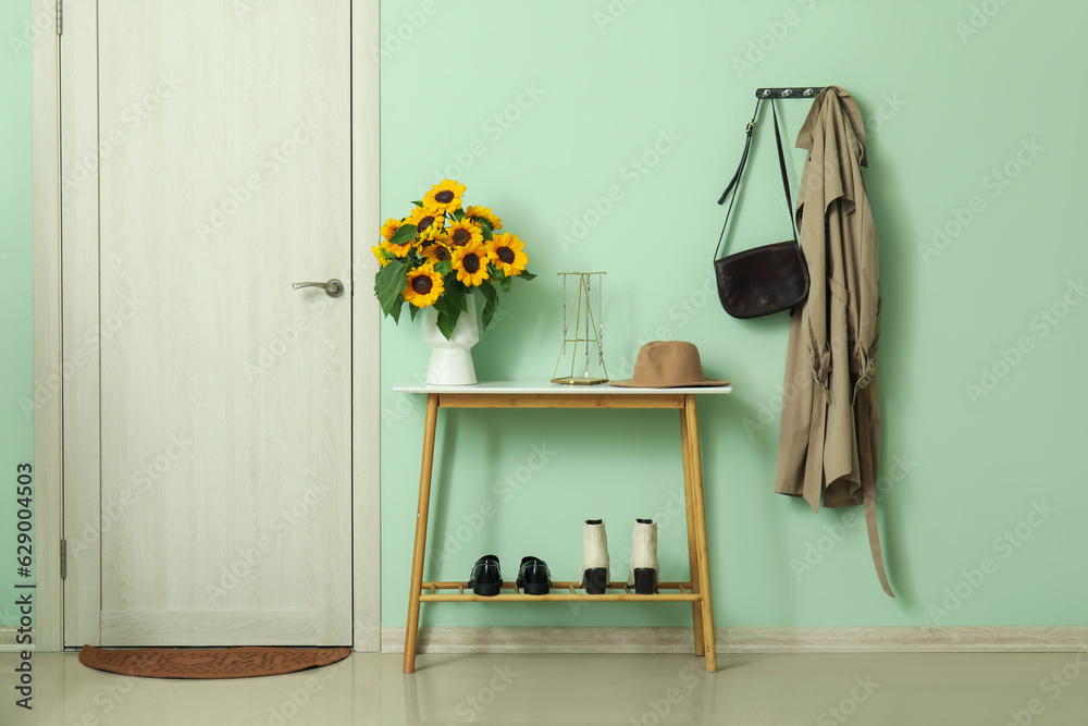 Vase with beautiful sunflowers on console table in hallway