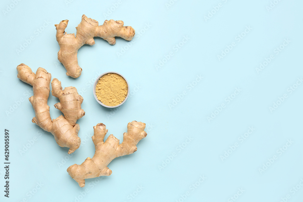 Fresh ginger roots and bowl with dried powder on blue background