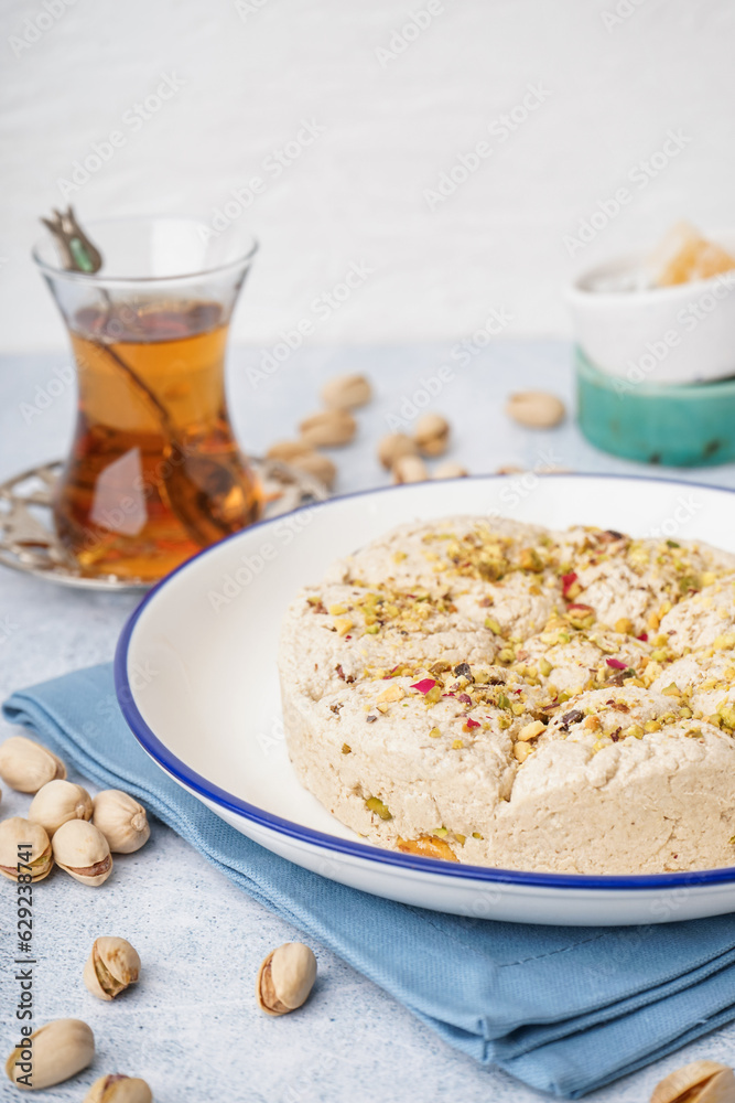 Plate of tasty Tahini halva with pistachios on light background, closeup