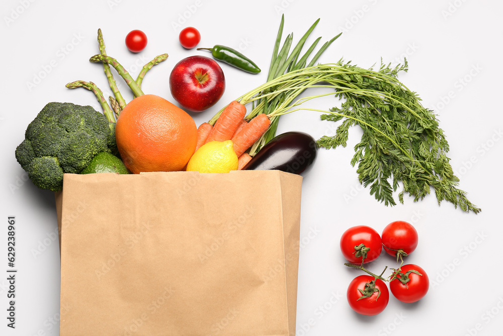 Paper bag with vegetables and fruits on grey background