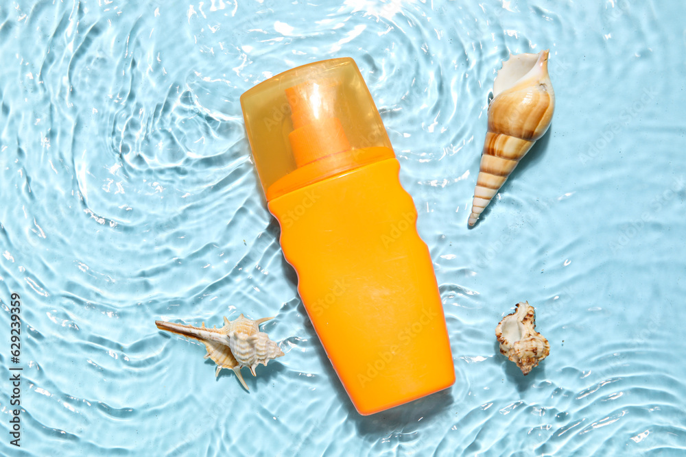 Sunscreen cream with starfishes and seashells in water on color background