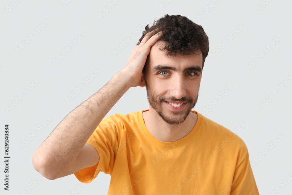 Young brunette man with stylish hairdo on light background, closeup