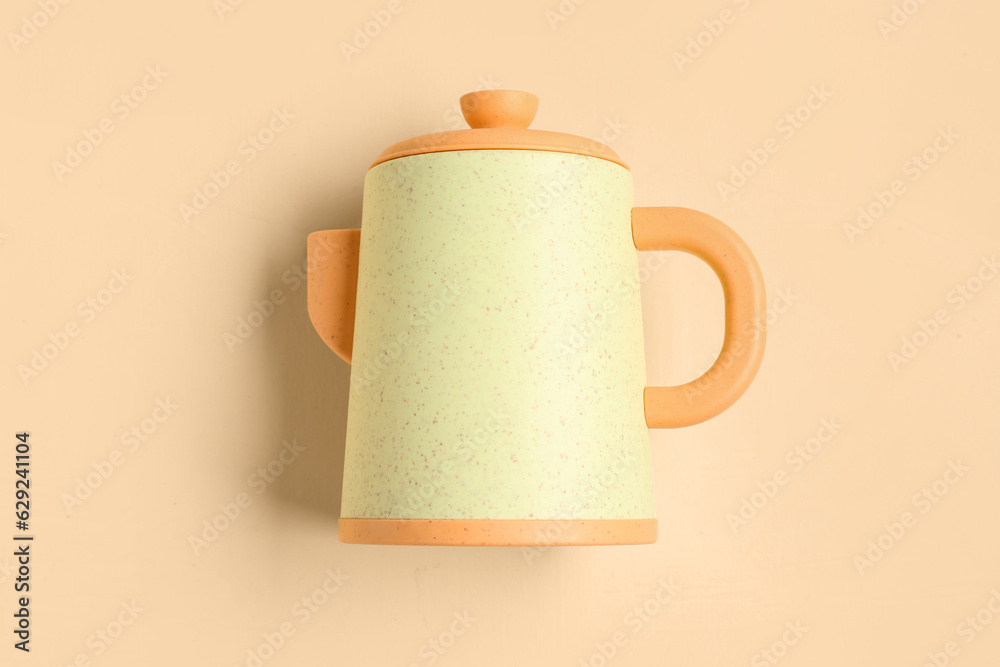 Yellow teapot for baby on pale orange background