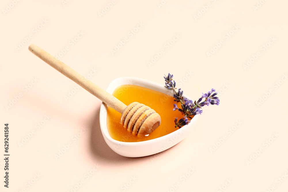 Bowl of sweet lavender honey, dipper and flowers on light background