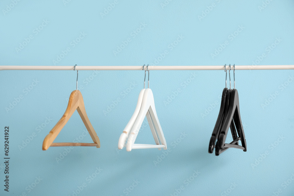 Rack with wooden clothes hangers on blue background