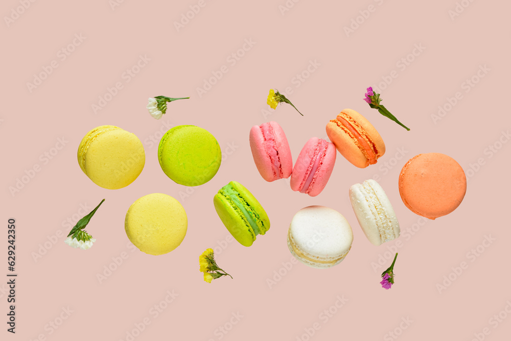 Flying sweet macaroons and beautiful flowers on pink background