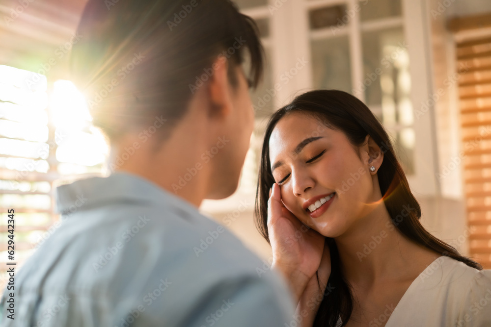 Asian young man and woman kissing each other in living room at home. 