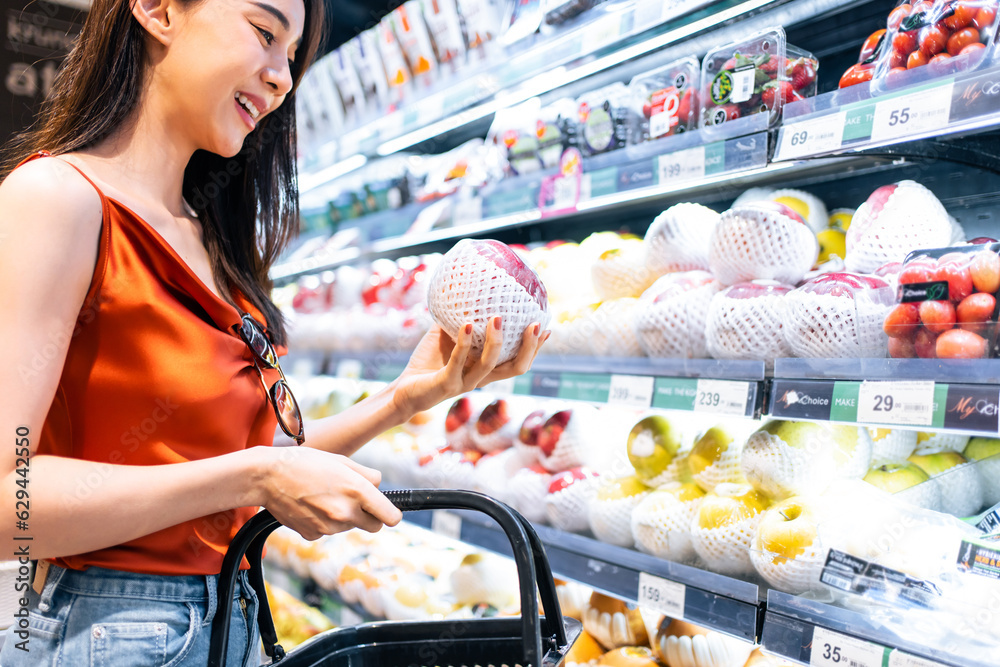 Asian young beautiful woman holding grocery basket walk in supermarket. 