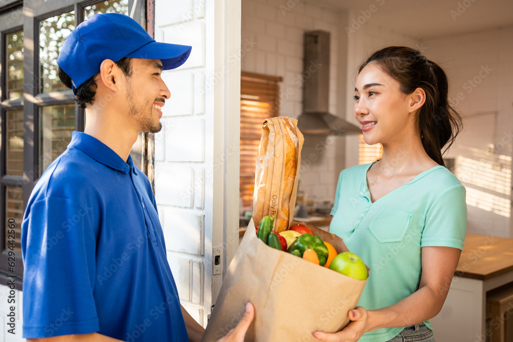 Asian young delivery man delivering package to female customer at home. 