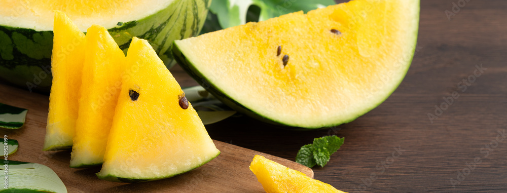 Sliced yellow watermelon in a plate on wooden table background.