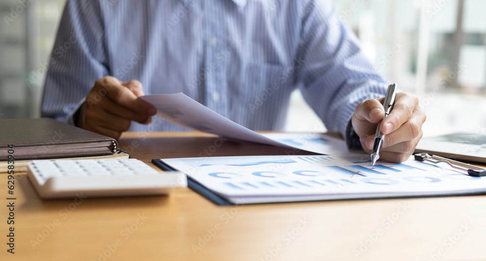 Businessman working with laptop and analyzing charts on financial documents with calculator.