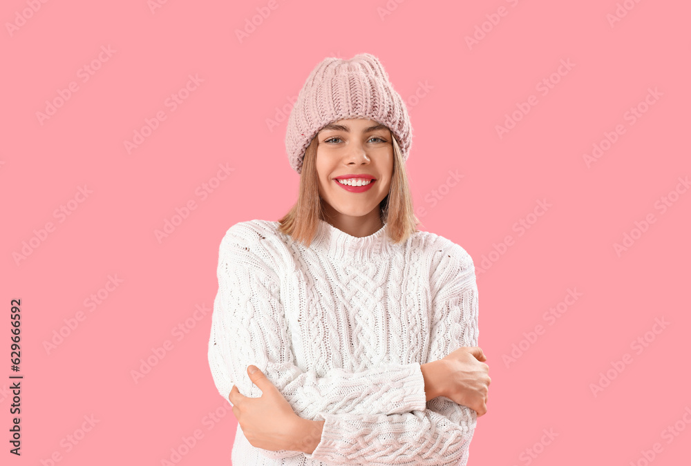 Frozen young woman in winter clothes on pink background