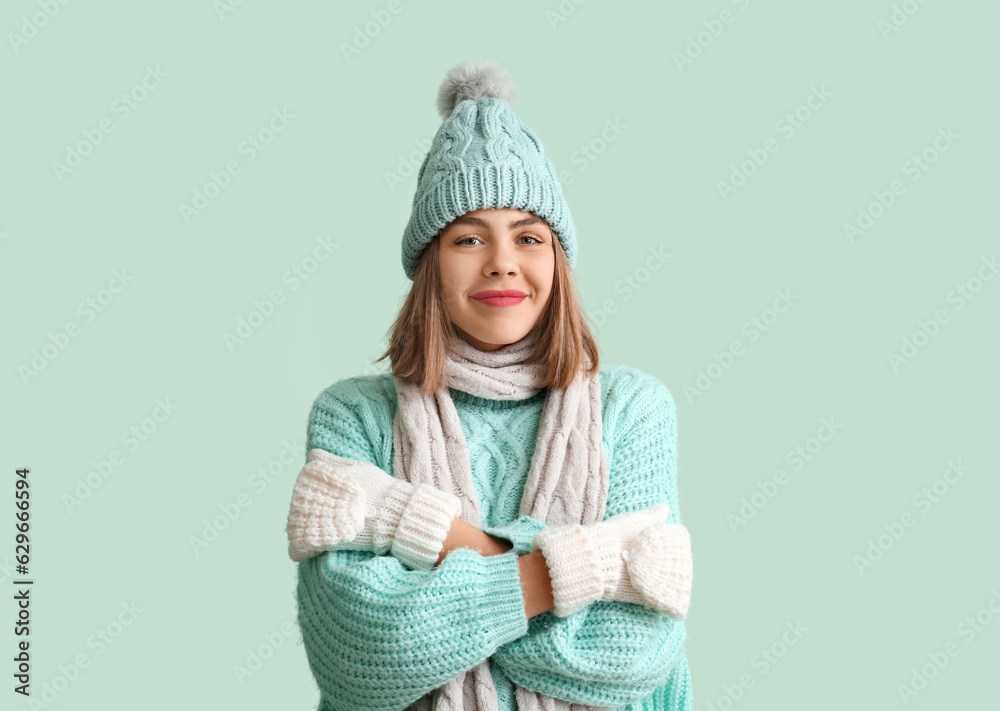 Frozen young woman in winter clothes on green background