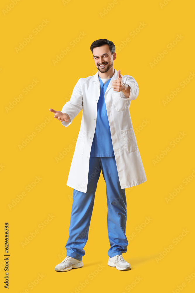 Male dentist showing thumb-up on yellow background