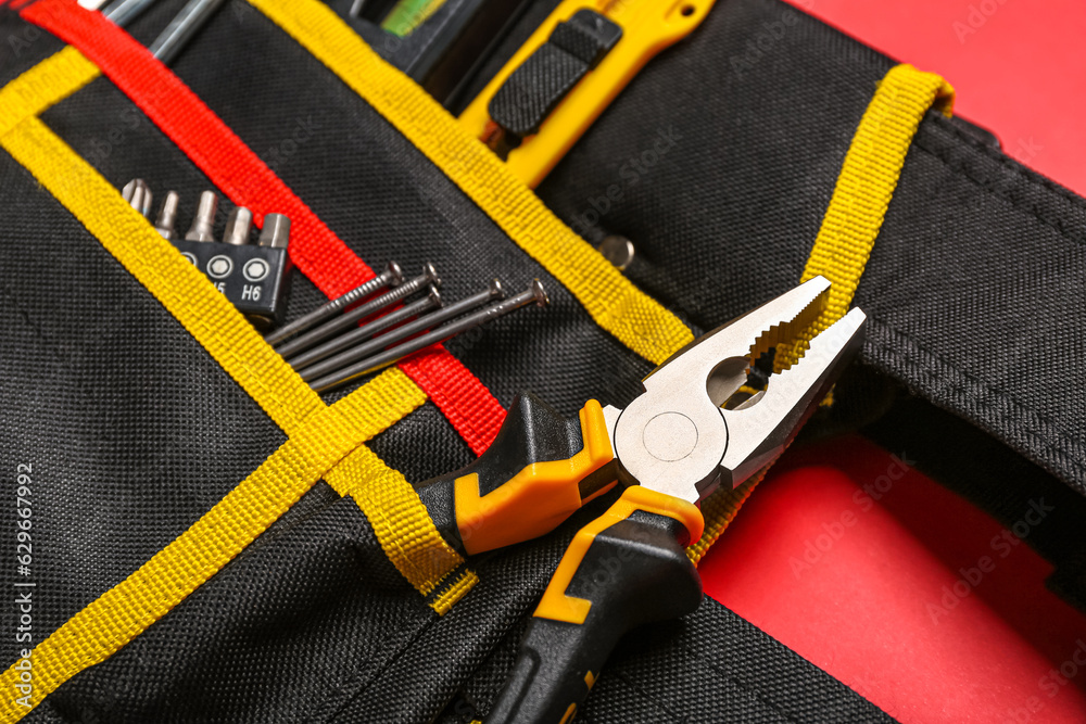 Belt with pliers and tools on red background