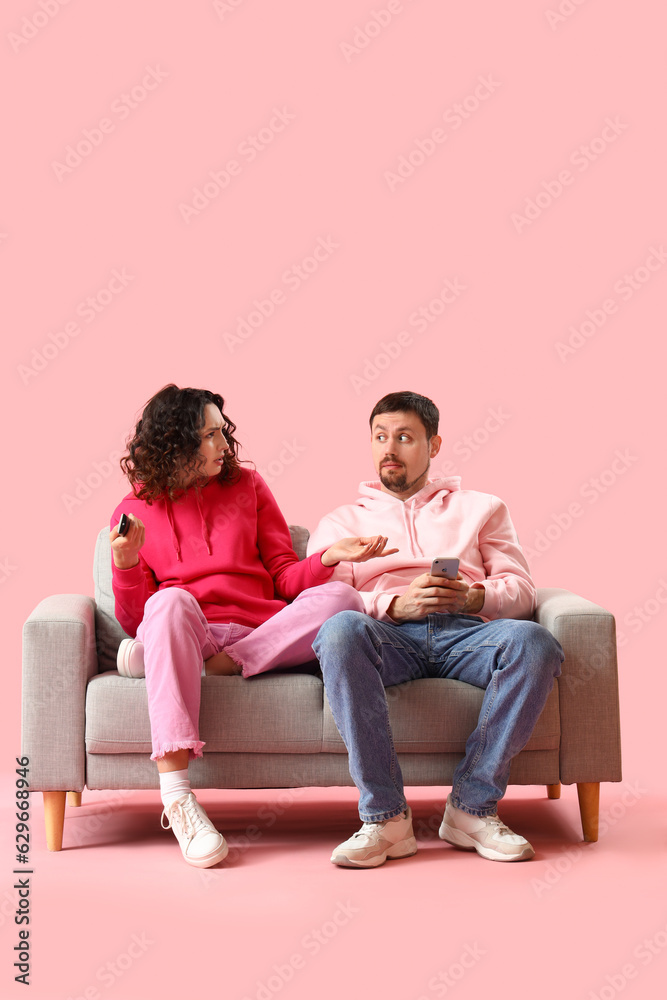 Young couple watching TV on pink background