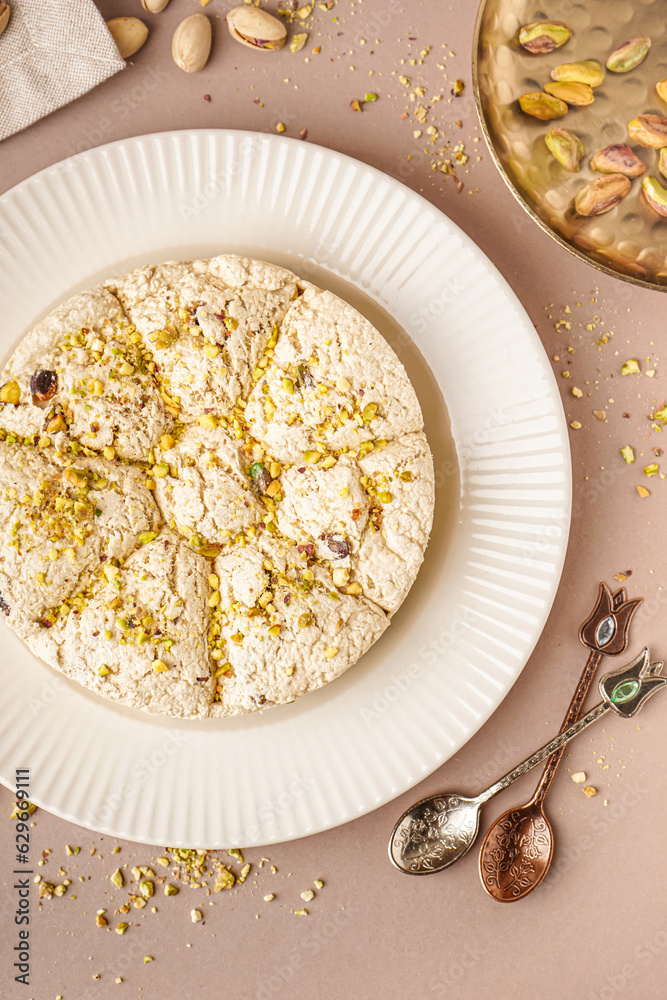 Plate of tasty Tahini halva with pistachios on beige background