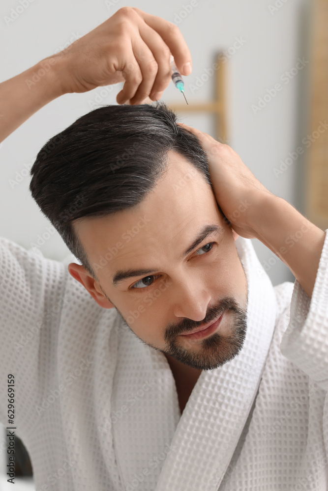 Handsome man with injection for hair growth in bathroom, closeup