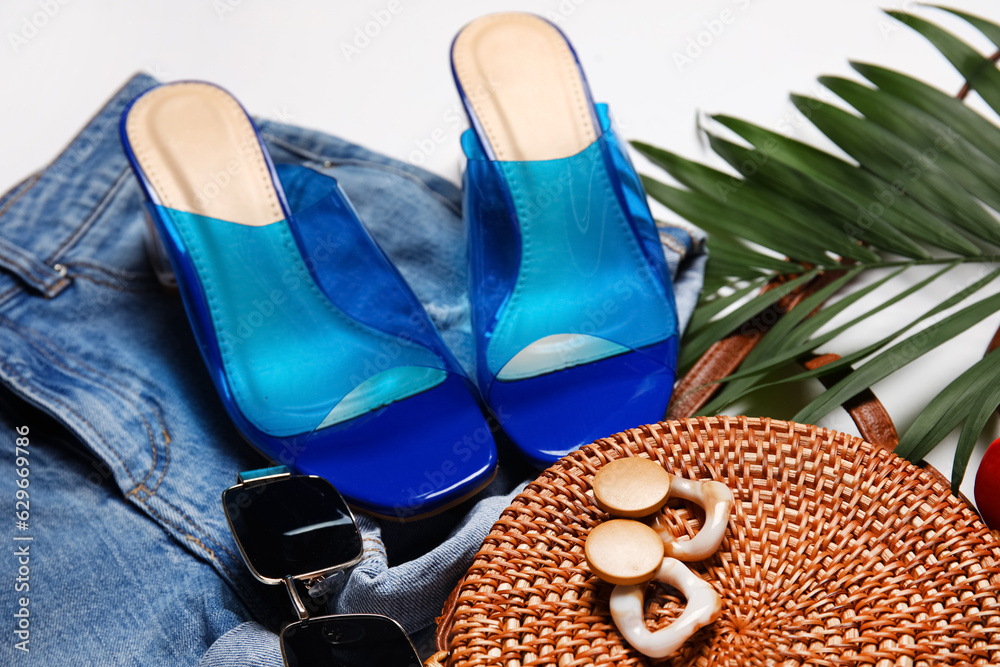 Composition with stylish female shoes, clothes, accessories and palm leaf on light background, close