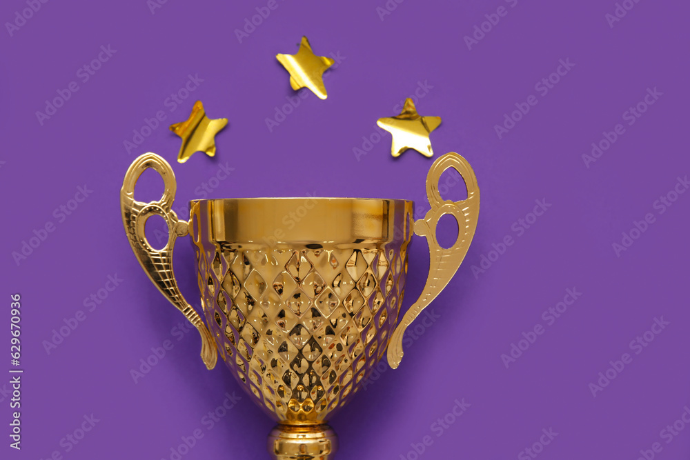 Gold cup with stars on purple background, closeup