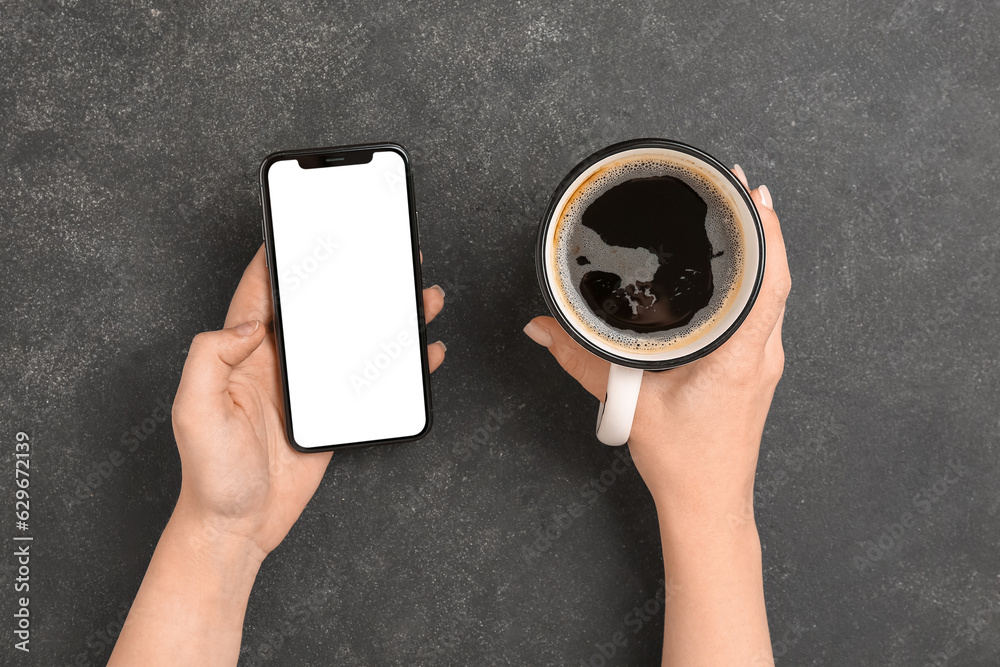 Woman with cup of coffee and mobile phone on dark background