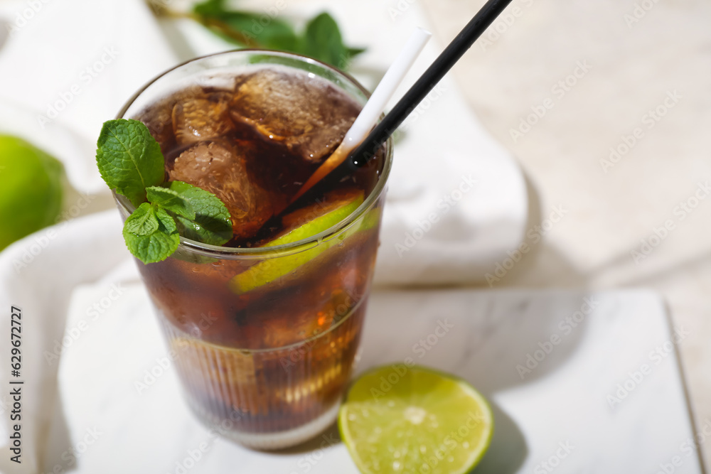 Glass of tasty Cuba Libre cocktail on light background, closeup