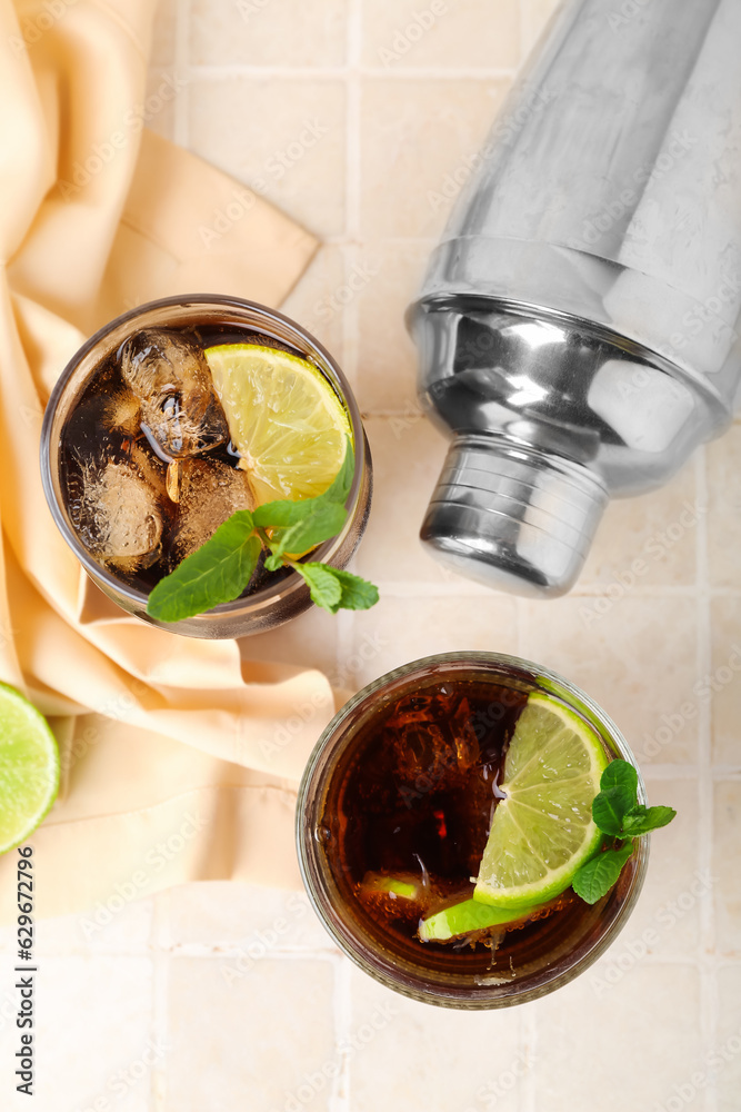 Glasses of tasty Cuba Libre cocktail on light tile background