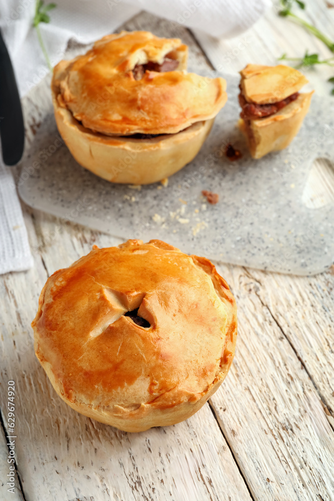 Tasty meat pot pies on light wooden background