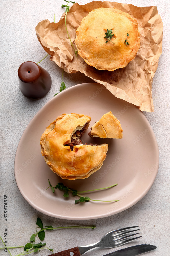 Plate with tasty meat pot pies on light background