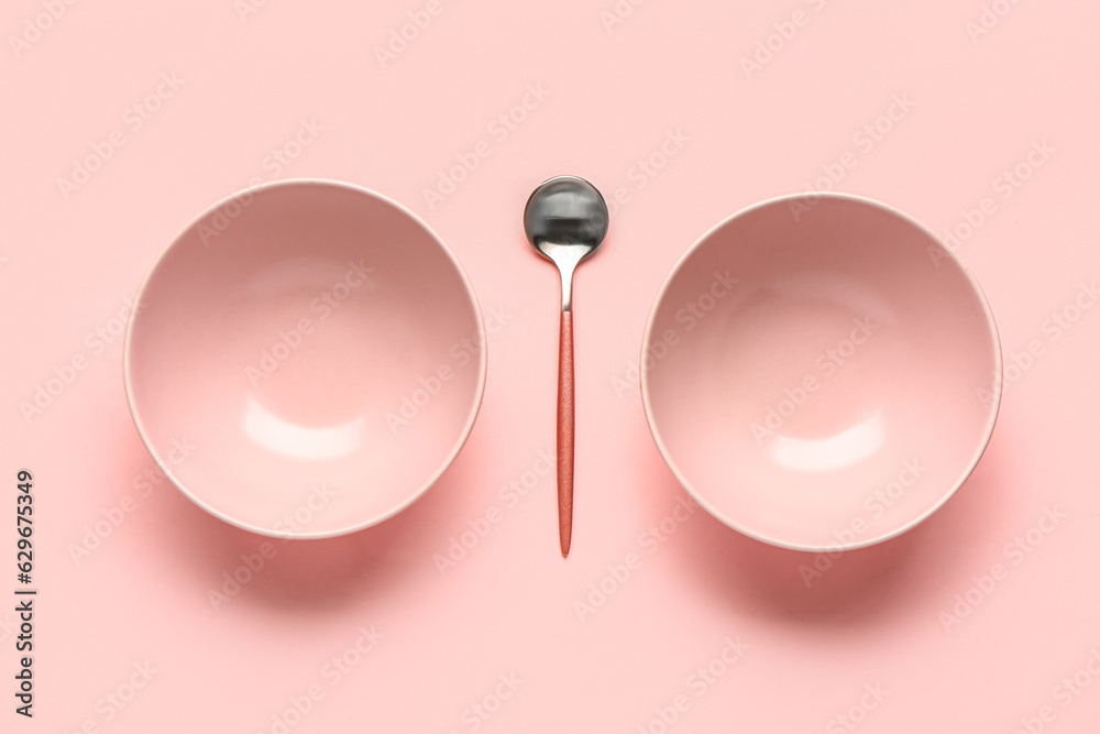 Composition with clean bowls and spoon on pink background