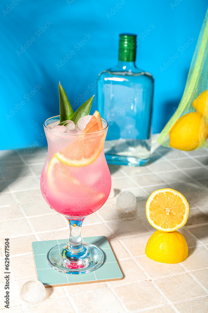 Fresh summer cocktail with grapefruit on tile table near blue wall