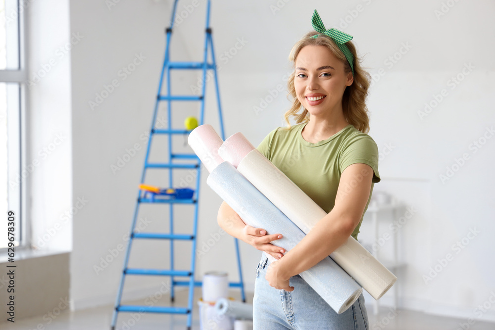 Young woman with wallpaper rolls at home