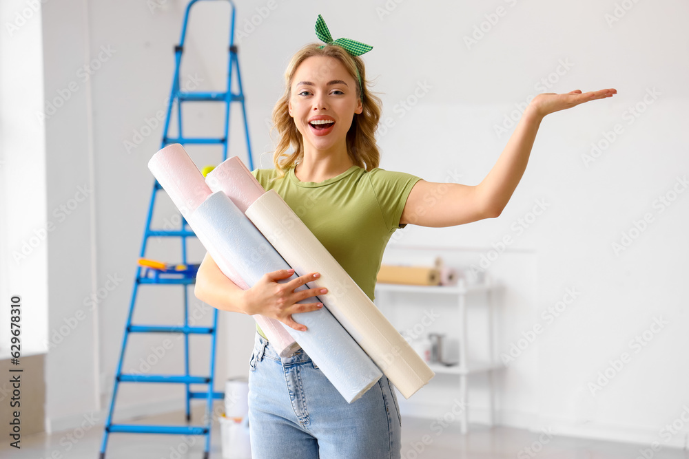 Young woman with wallpaper rolls at home