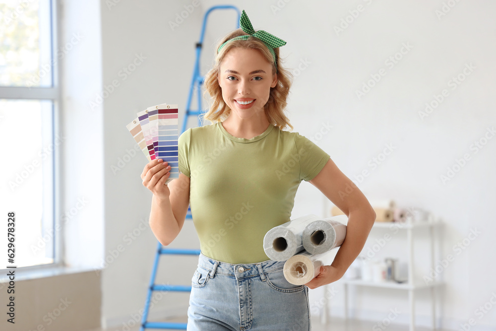 Young woman with wallpaper rolls and paint color palettes at home