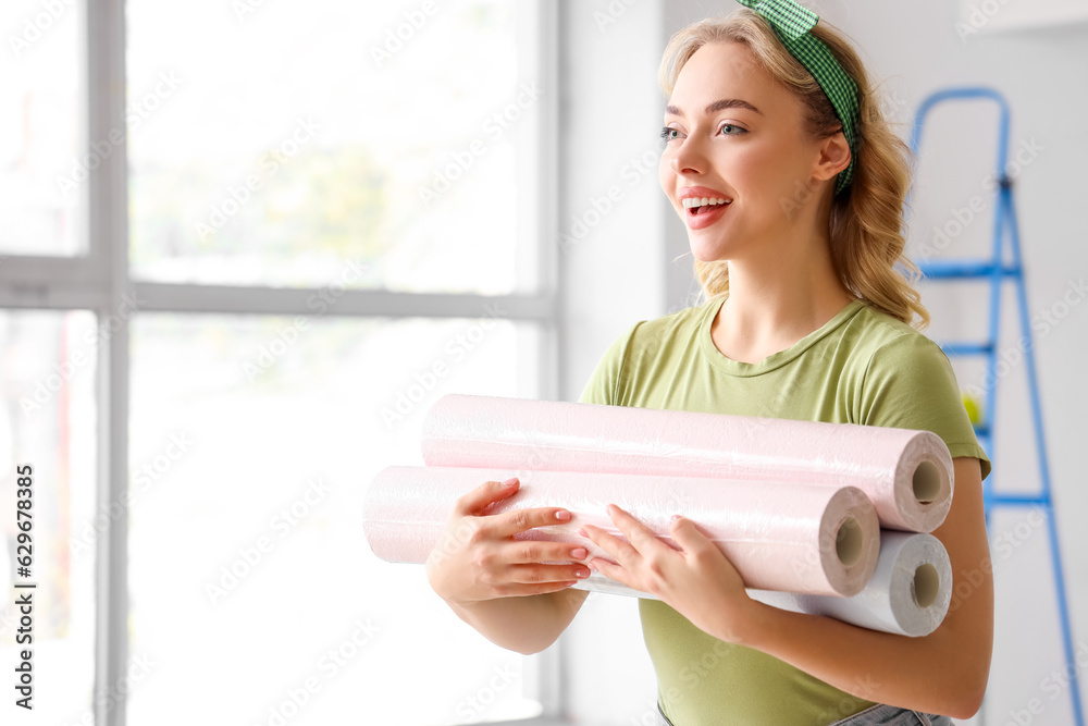 Young woman with wallpaper rolls at home