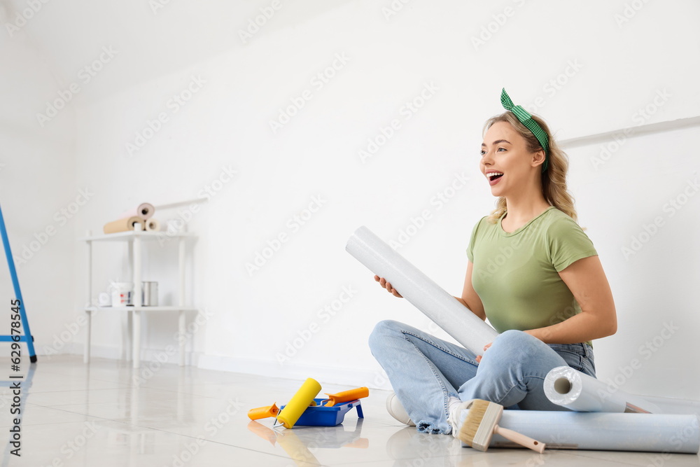 Young woman with wallpaper roll sitting at home