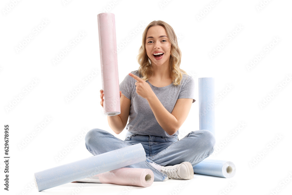 Young woman pointing at wallpaper roll on white background