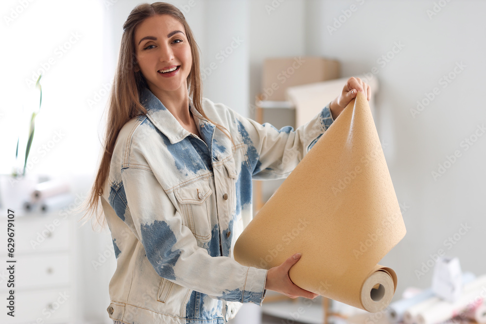 Young woman with wallpaper roll at home