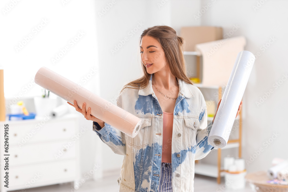 Young woman with wallpaper rolls at home