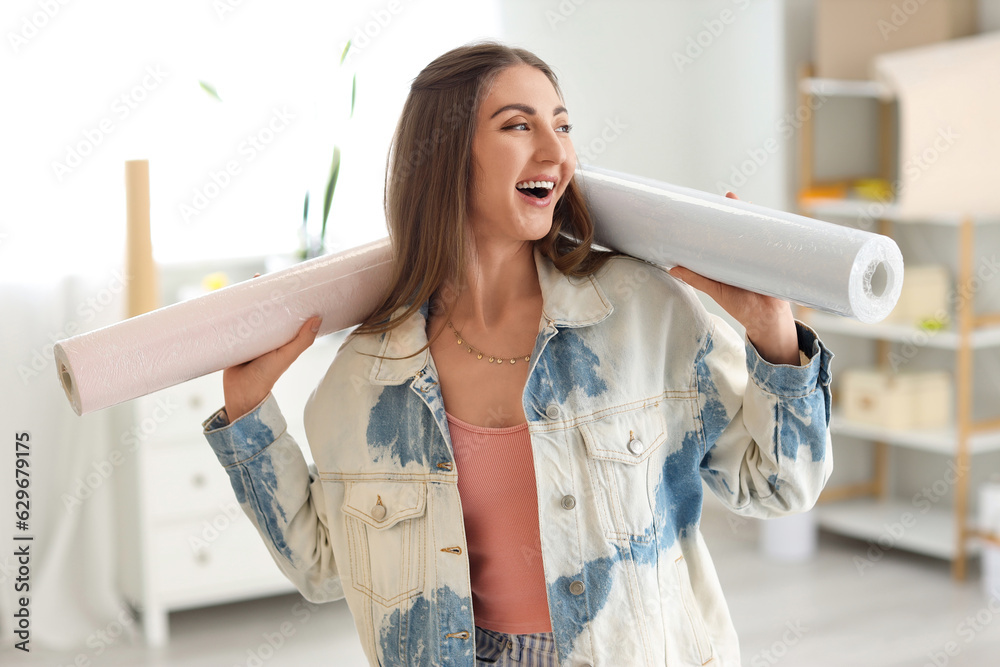 Young woman with wallpaper rolls at home