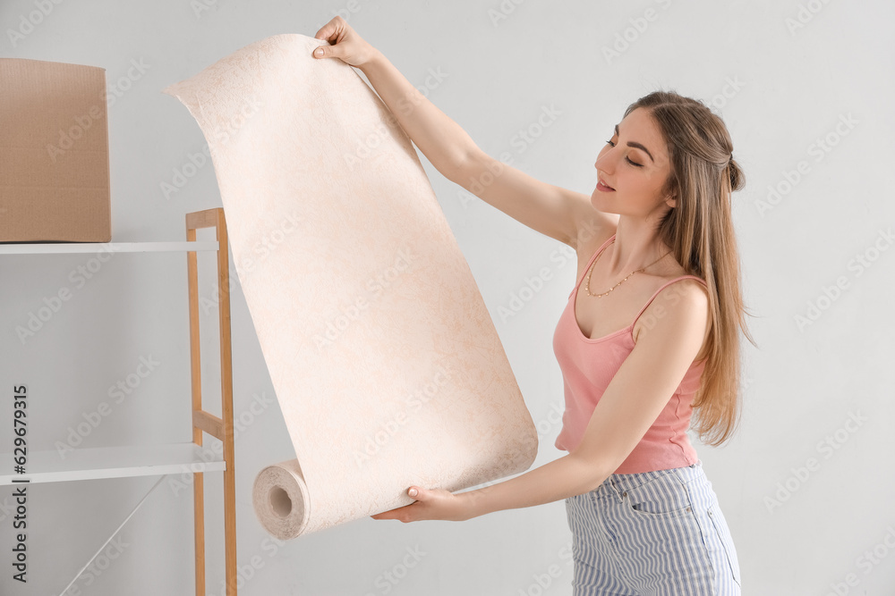 Young woman with wallpaper roll at home