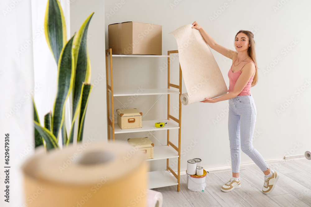 Young woman with wallpaper roll at home