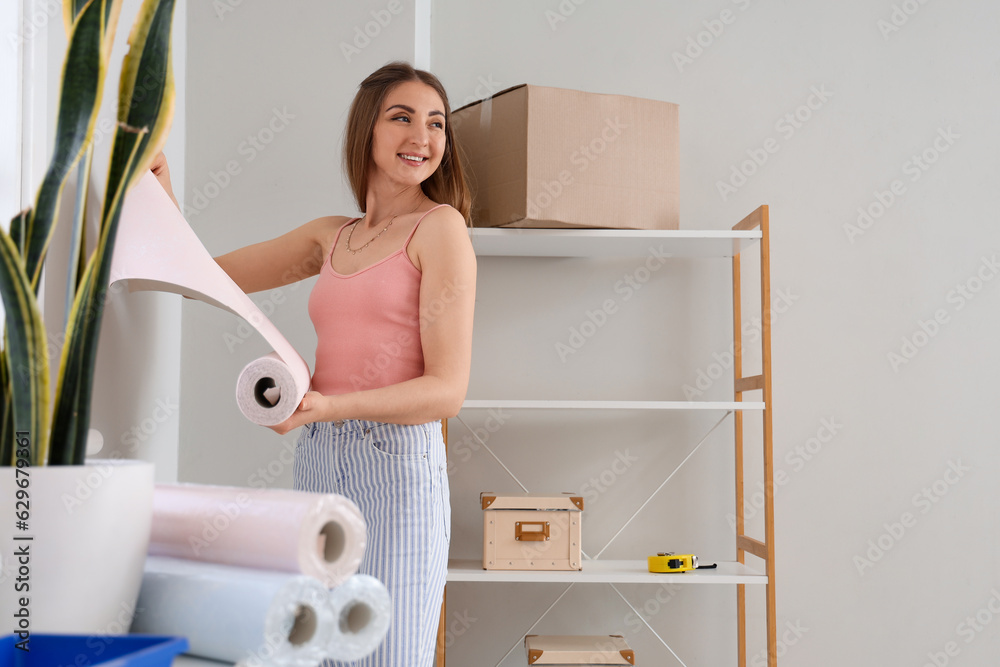 Young woman with wallpaper roll at home