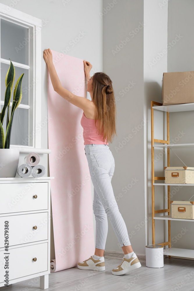 Young woman with wallpaper roll at home