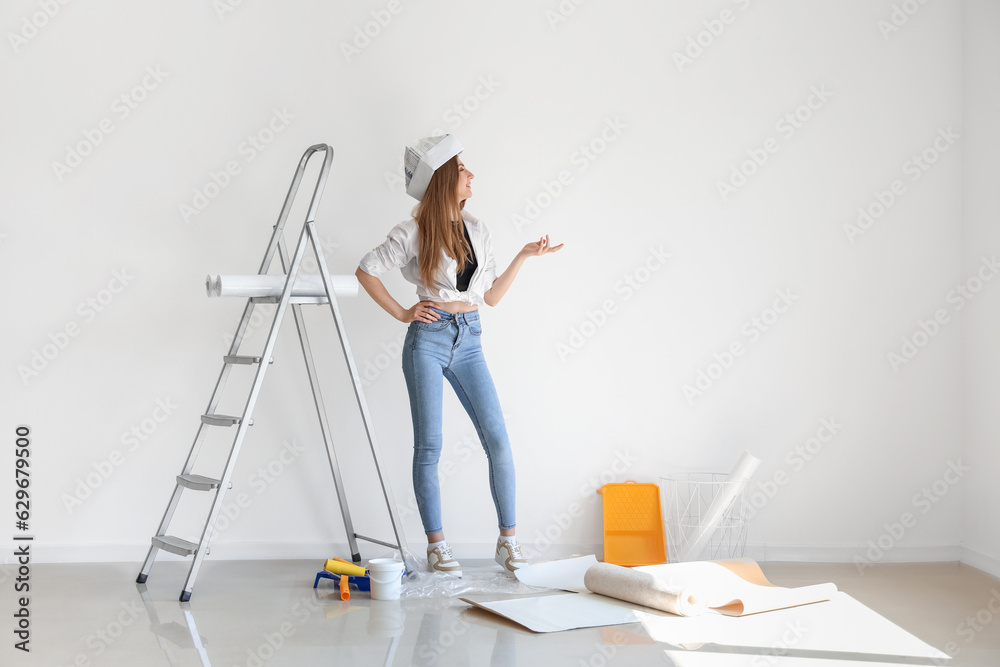 Young woman with wallpaper rolls in room